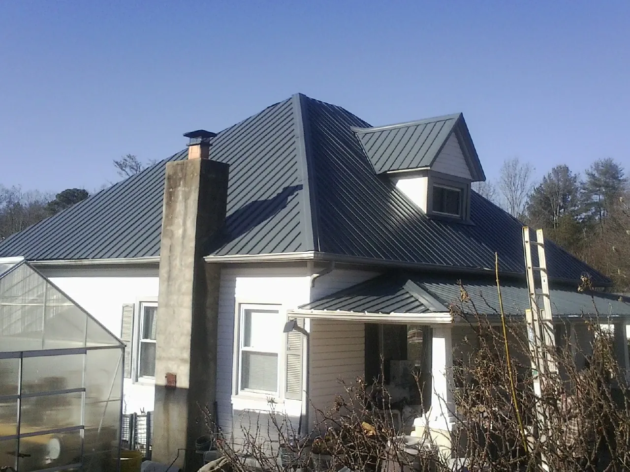 Dark blue standing seam metal roof on a white farmhouse with dormer — Slate & Tile Roof Repair by Roofing Brothers in Miami Gardens