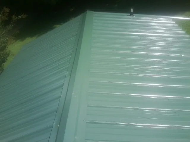 New green metal panels meeting at the ridge of a roof — Flat Roof Repair work by our crew in Miami Gardens