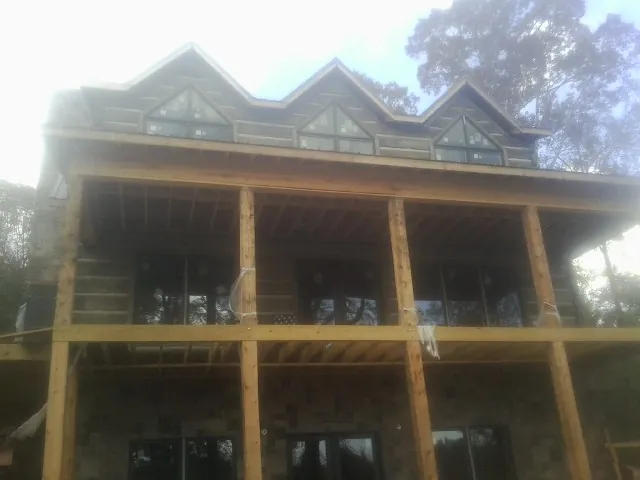 Dormers and porch framing on a large log home under construction — Roof Coating work by our crew in Miami Gardens