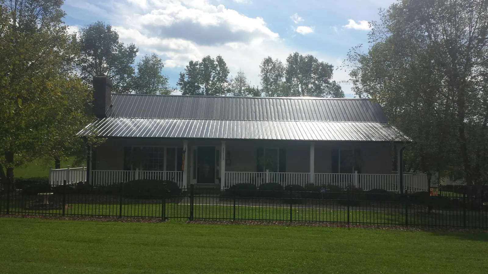 Gray metal roof on a brick ranch with a full width front porch — Gutter Guard Installation work by our crew in Miami Gardens
