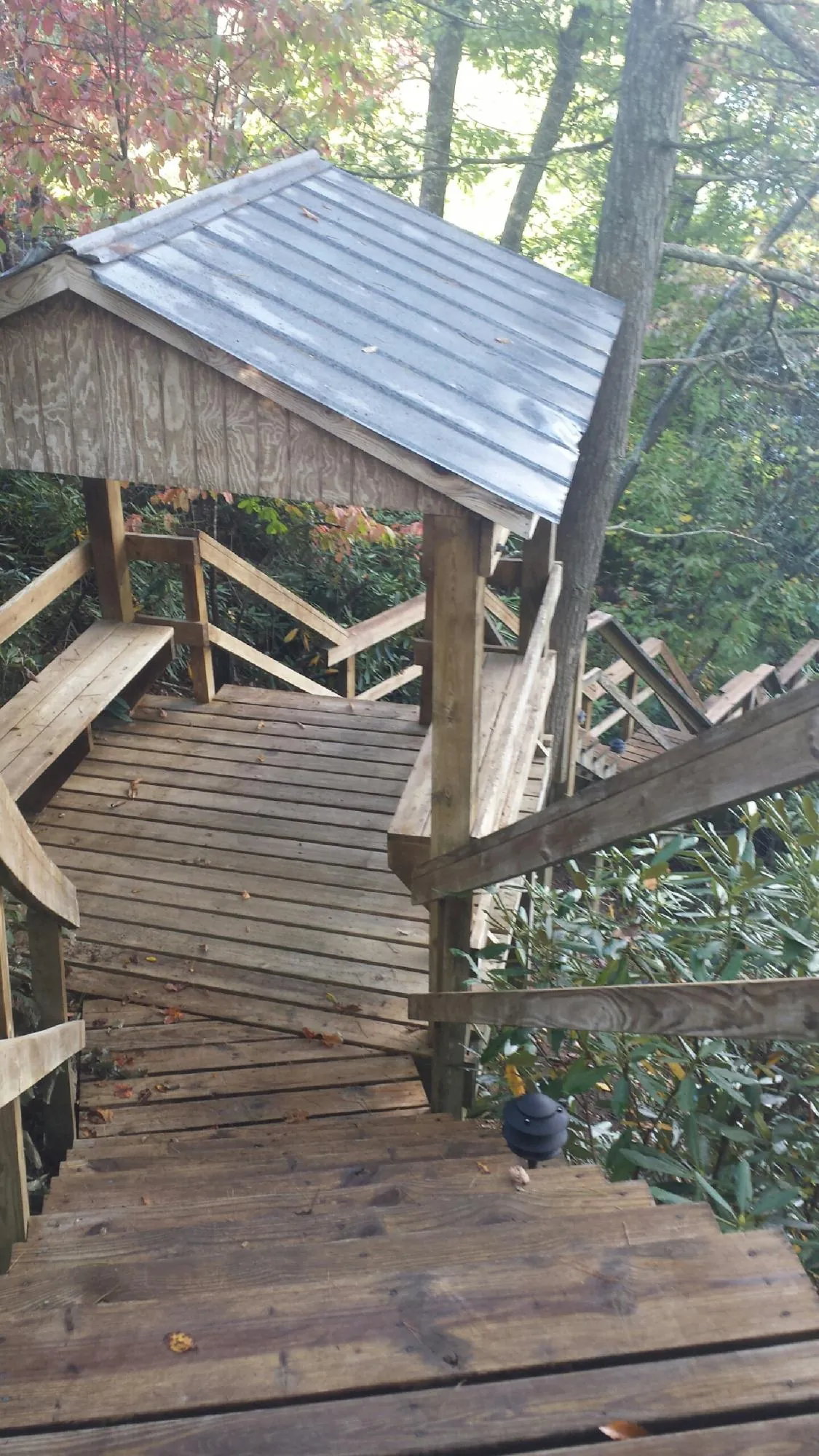 Metal roofed shelter over wooden steps on a wooded walkway — Skylight Repair & Installation work by our crew in Miami Gardens