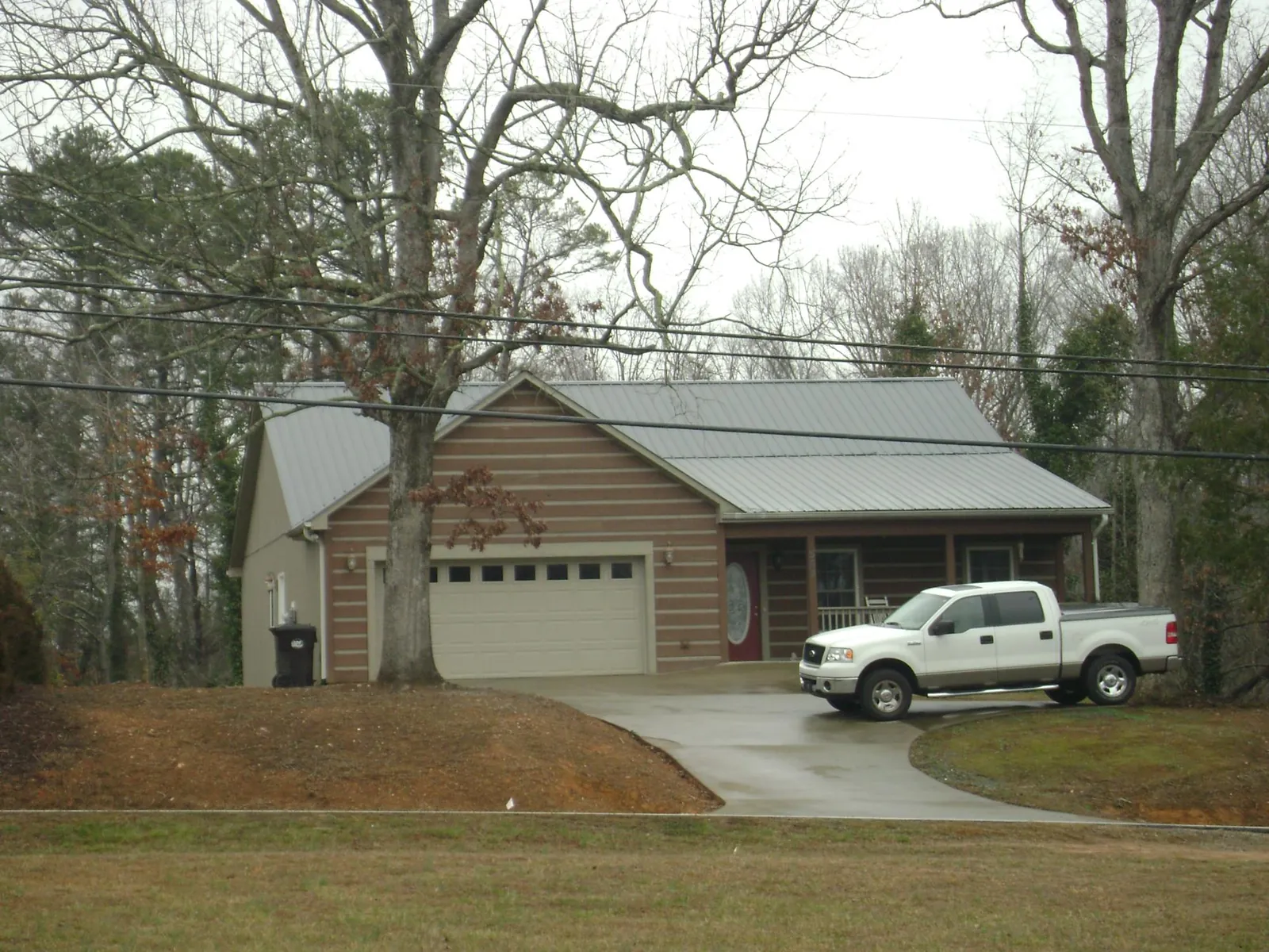 Gray metal roof on a log sided house with an attached two car garage in Miami Gardens