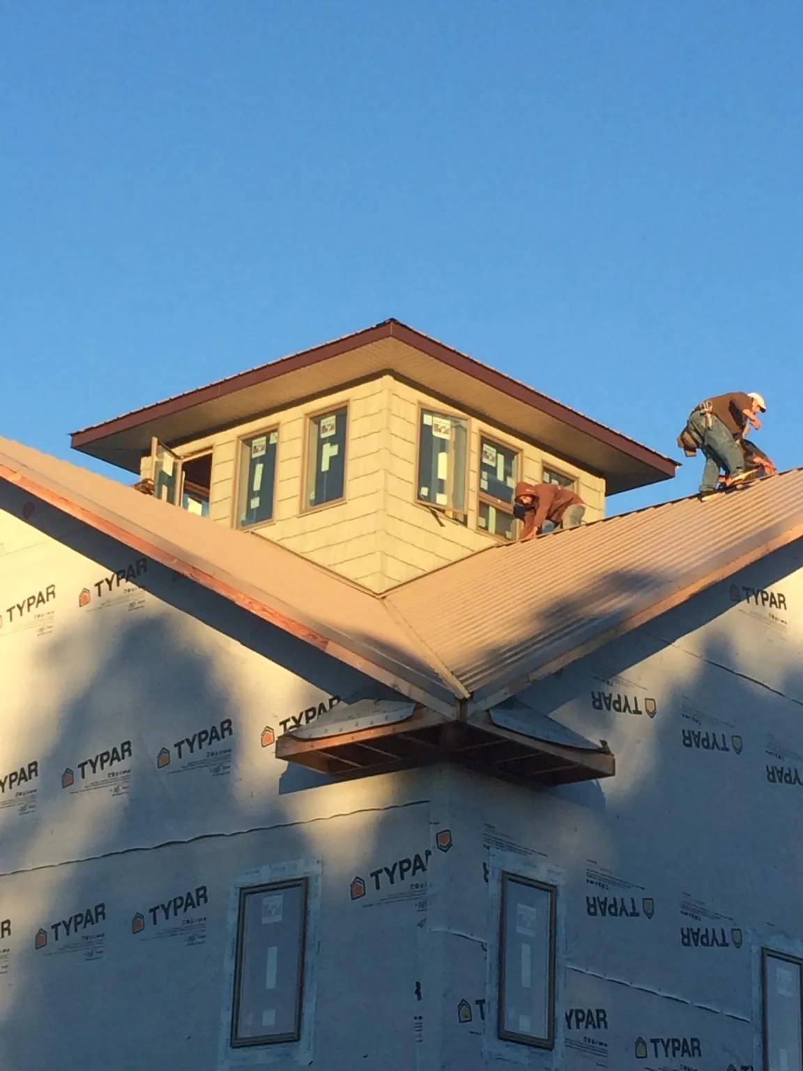 Roofers working around a rooftop cupola on a new metal roof at sunset — Roof Waterproofing in Miami Gardens by Roofing Brothers